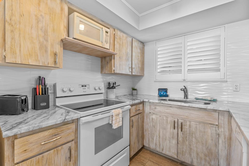 Beautifully designed kitchen with detailed wood cabinetry, modern appliances, and marble-style counters for a stylish cooking experience.