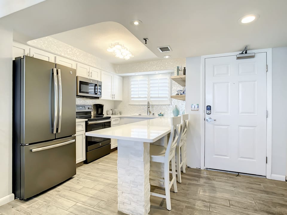 Fully equipped kitchen with stainless steel appliances, bar seating, and ample countertop space for dining and prep.