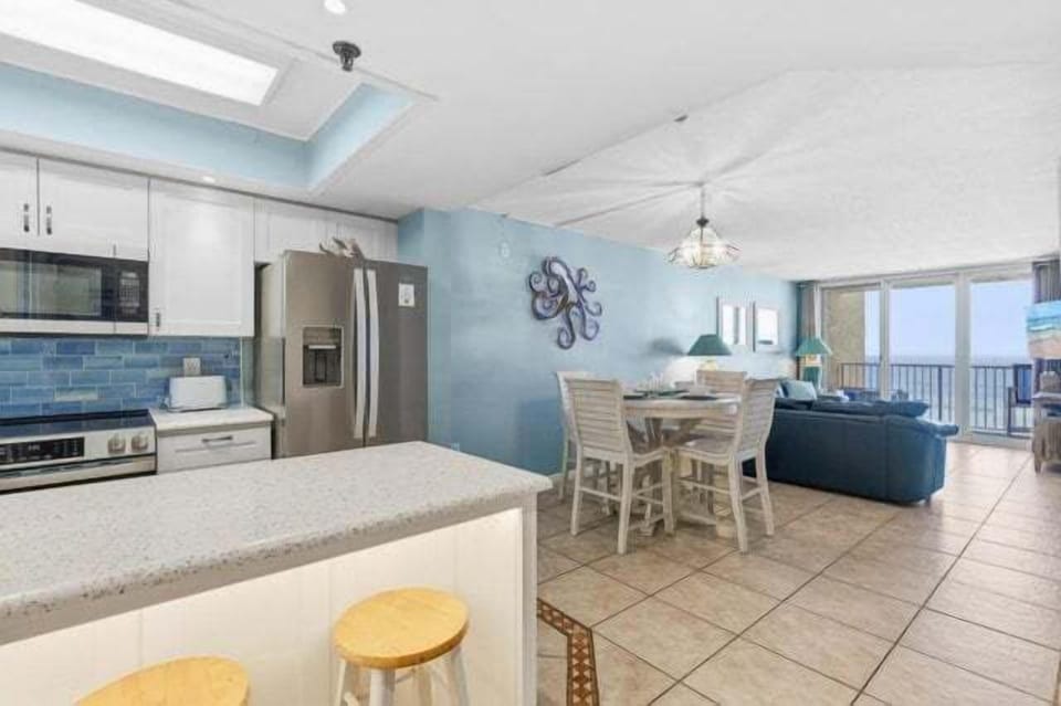 Enjoy an open-concept layout featuring a modern kitchen, dining area, and living space with ocean views. Perfect for your beach stay, gather, dine, and relax in this bright coastal retreat just steps from the shore.