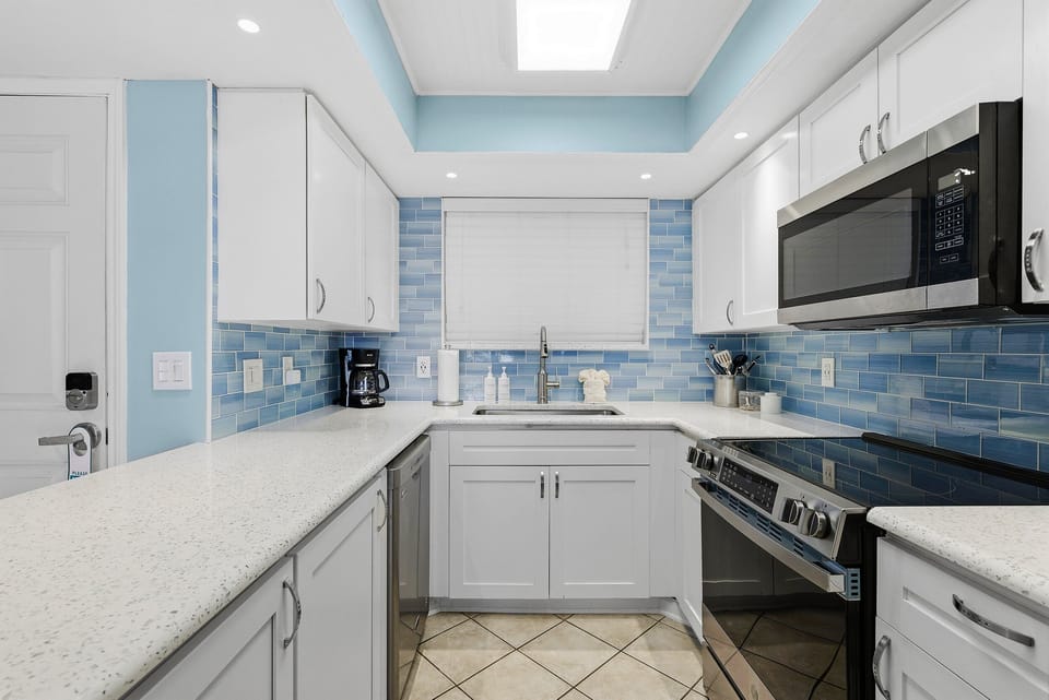 Enjoy a light-filled coastal kitchen featuring modern appliances, sleek countertops, and blue tile backsplash—perfect for your beach stay. Ideal for cooking after a day by the ocean in this relaxing vacation retreat.