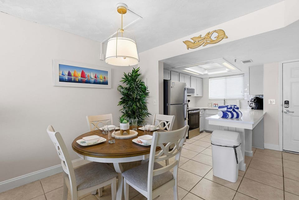 Enjoy your beach stay with this inviting dining area and fully equipped kitchen, perfect for meals and gatherings. Bright coastal décor and open layout create a relaxing space just steps from the beach.