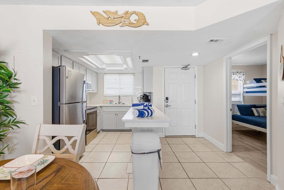 This inviting beach stay features a fully equipped kitchen with modern appliances, open layout, and dining space. Perfect for easy meals and relaxing after a day at the beach, with comfortable sleeping areas nearby.