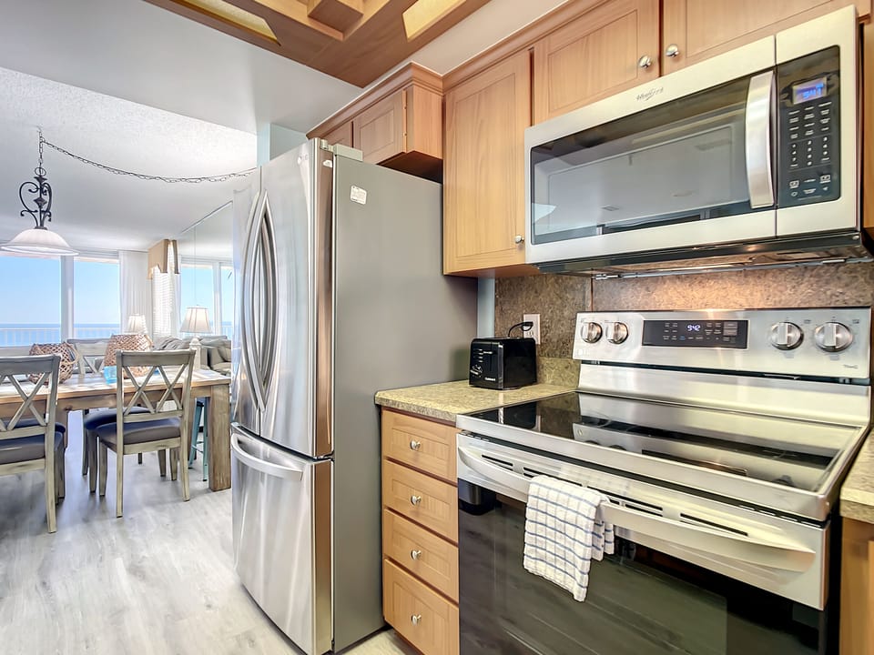 Fully equipped kitchen with stainless steel appliances, granite countertops, and an open layout, perfect for cooking with a view.
