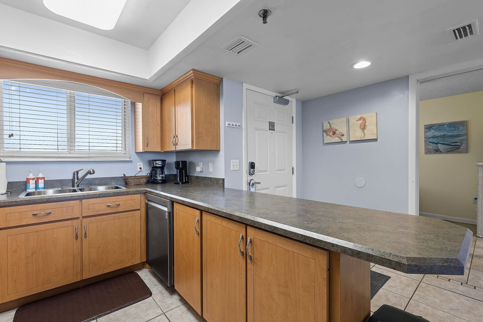 Enjoy a breezy beach stay with this spacious kitchen featuring ample counter space, modern amenities, and a breakfast bar—perfect for easy oceanfront meals.