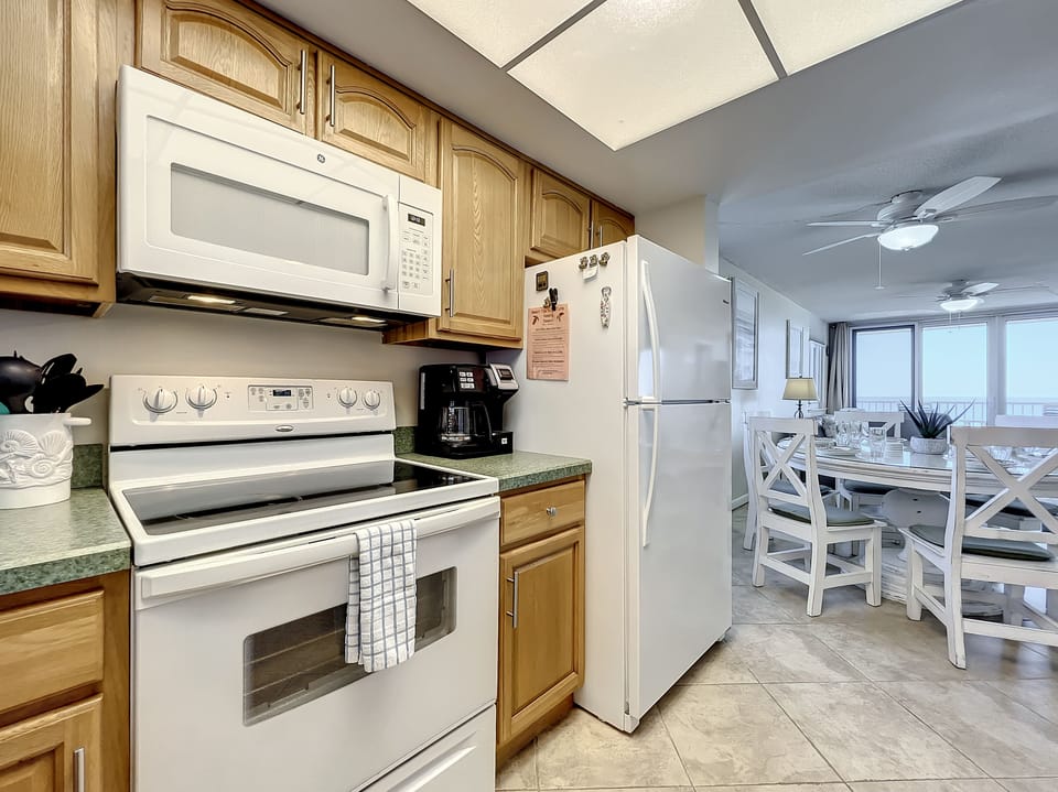 A functional kitchen opens to a cozy dining space, featuring modern appliances and bright ocean views, perfect for preparing and enjoying meals with family and friends.