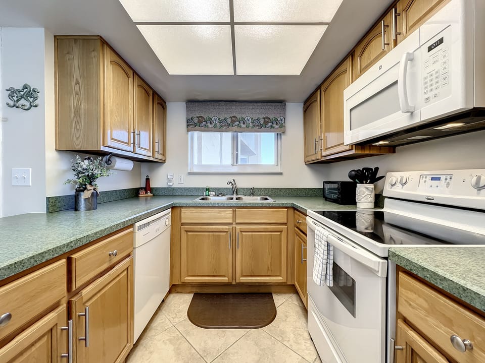 A bright, inviting kitchen featuring ample cabinetry, modern appliances, and spacious countertops. Perfect for cooking delicious meals during your beachside stay.