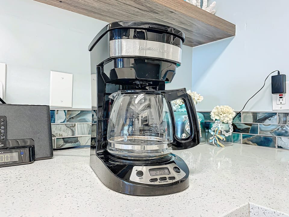 Sleek coffee maker on a sparkling countertop with ocean-inspired backsplash and charming coastal decor.