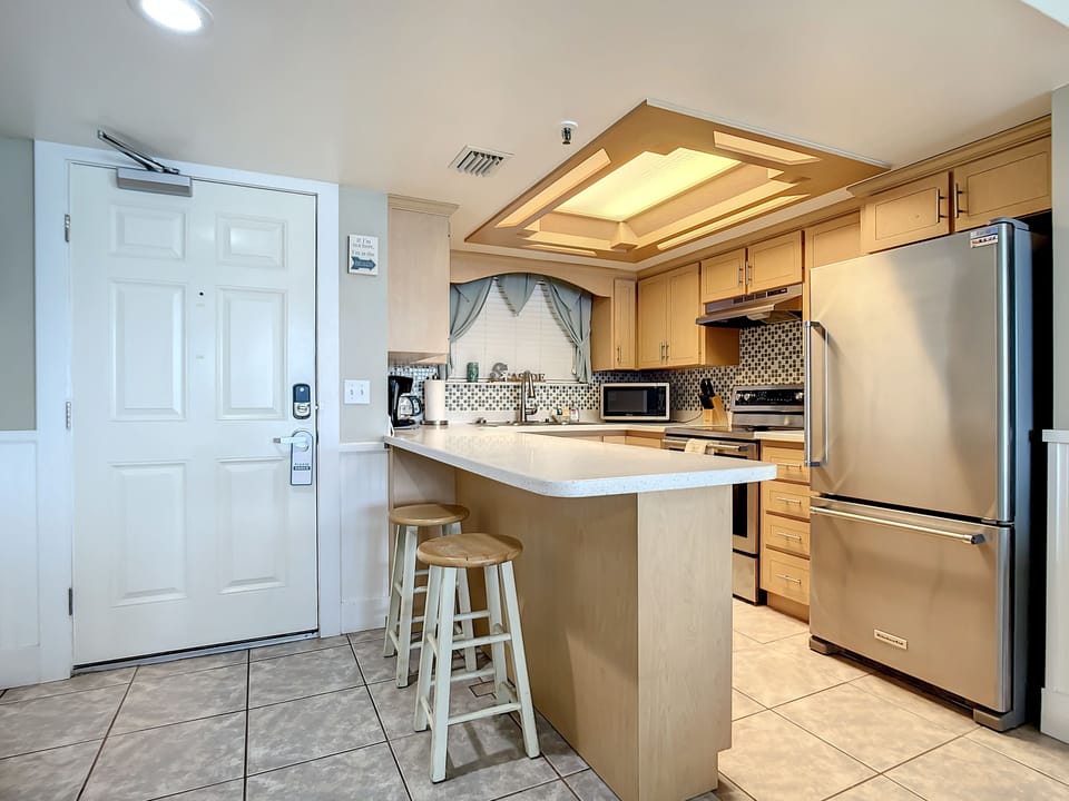 This modern kitchen features stainless steel appliances, ample counter space, and a cozy breakfast bar with seating. Perfect for preparing meals and enjoying casual dining during your stay, the space is both functional and inviting.