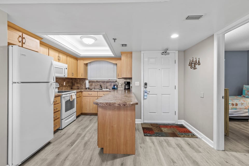 This inviting kitchen features a spacious breakfast bar, modern appliances, and ample counter space. The open layout offers easy access to the living area and bedrooms, creating a functional and welcoming beachside living space.