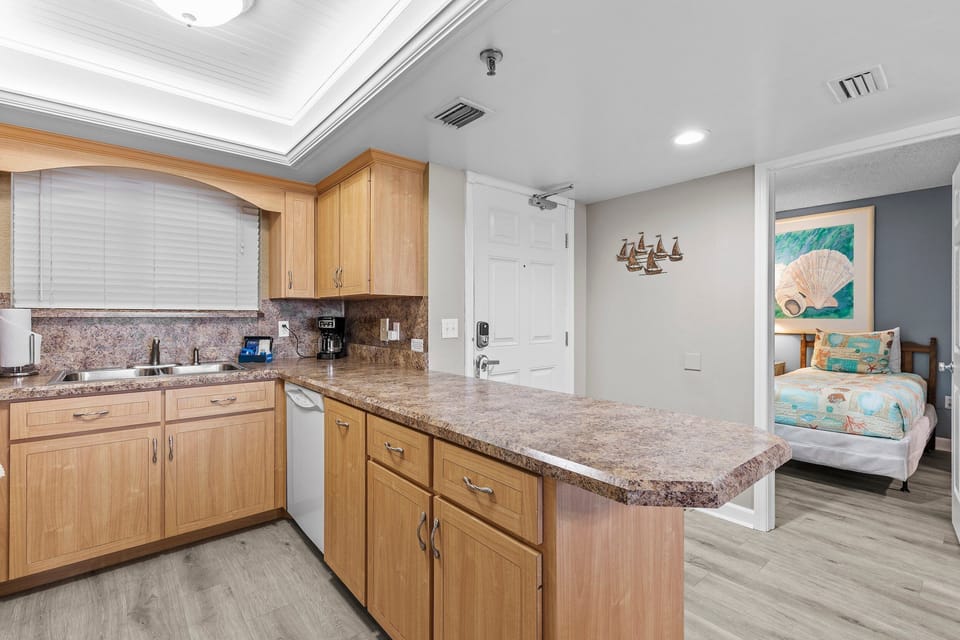 This open kitchen offers plenty of counter space, modern cabinetry, and a convenient breakfast bar. Perfect for preparing meals and entertaining, the kitchen connects seamlessly to the living and sleeping areas for a relaxed beachside experience.