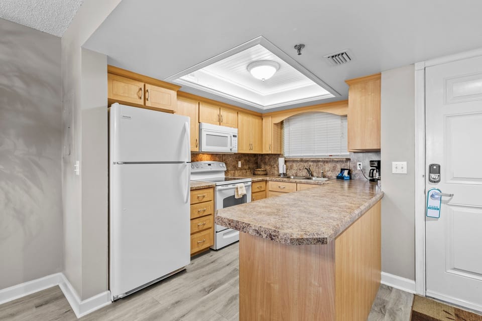 This well-lit kitchen offers ample counter space, modern appliances, and plenty of storage. With its convenient breakfast bar and open layout, it's perfect for preparing meals and enjoying casual dining in a relaxed beachside atmosphere.