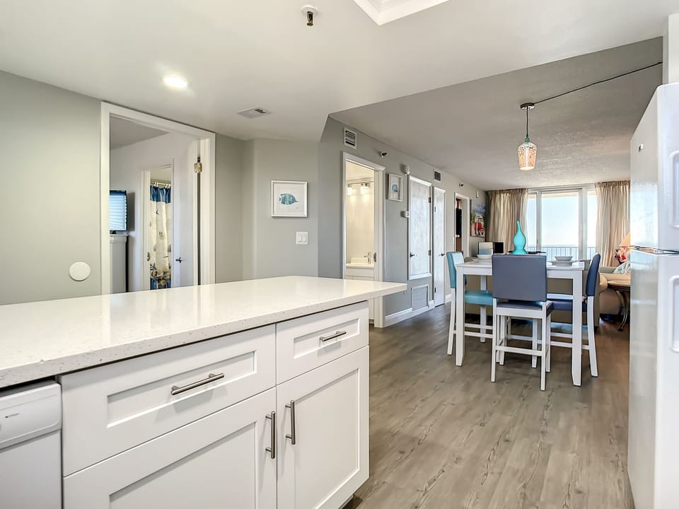 Open kitchen with sleek counters leading to a dining area, perfect for shared meals and relaxation.