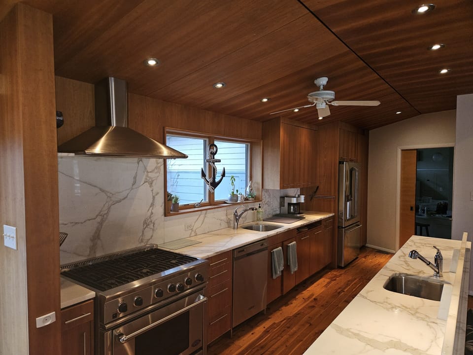Kitchen with gas range, marble counter tops and GE Café fridge. prep sink