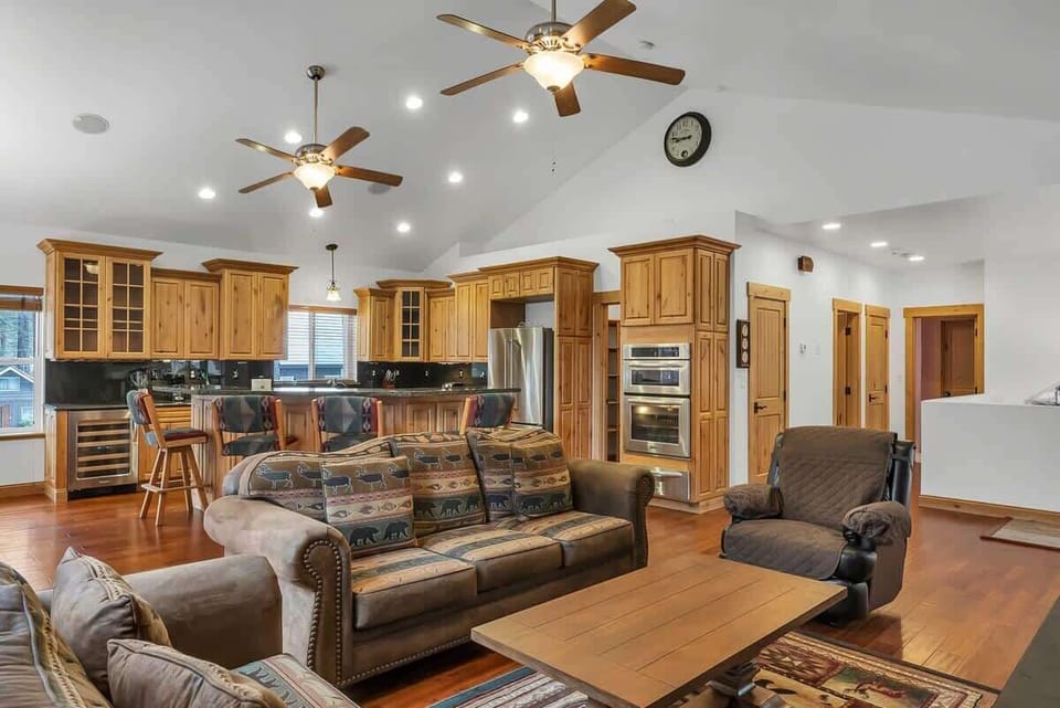The upstairs main living space features a bright and open kitchen/dining/living room with high ceilings and windows all around filling the area with natural light.