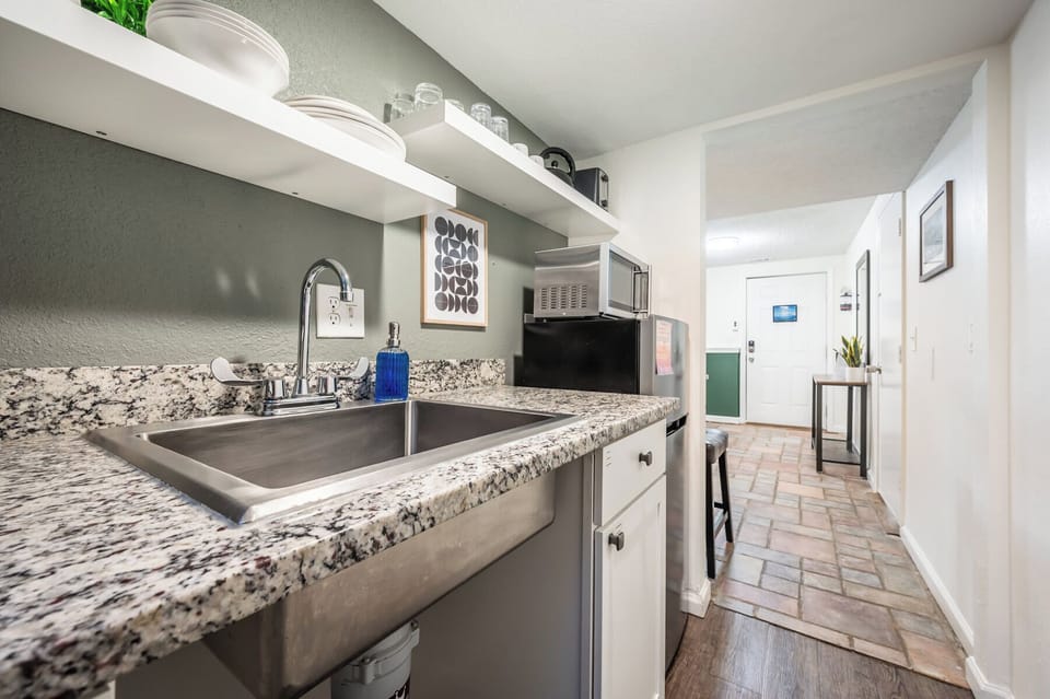 Compact yet efficient, the kitchenette offers everything you need for light meals—featuring a granite countertop, microwave, mini fridge, Keurig coffee maker, and open shelving stocked with essentials.







