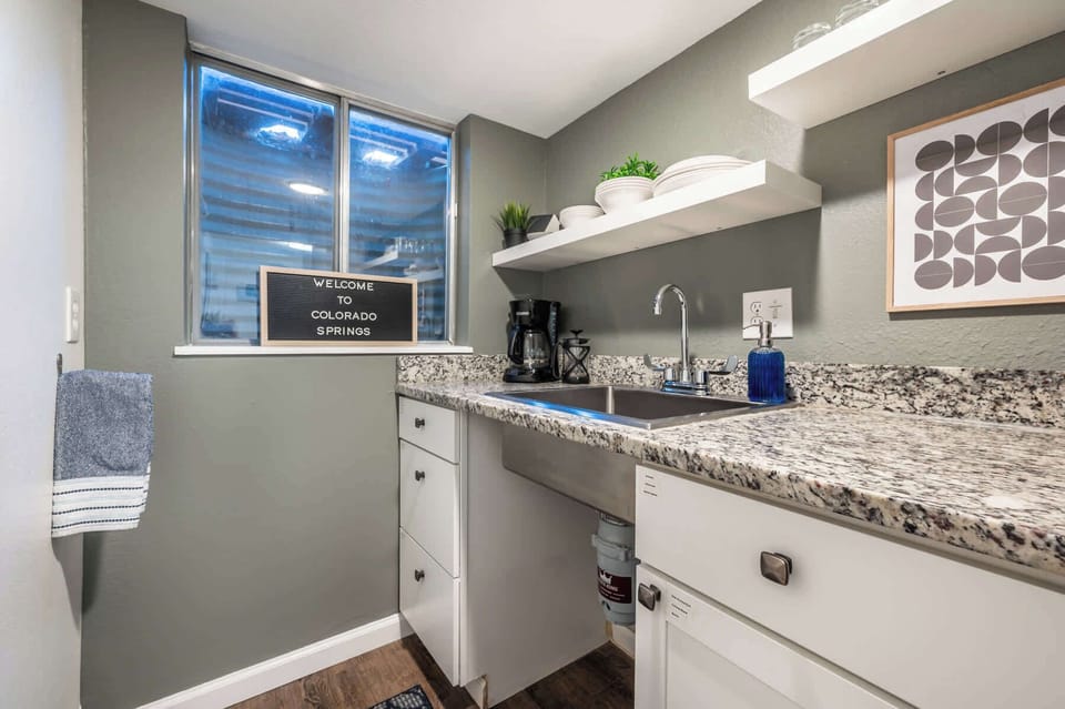 Compact yet efficient, the kitchenette offers everything you need for light meals—featuring a granite countertop, microwave, mini fridge, Keurig coffee maker, and open shelving stocked with essentials.







