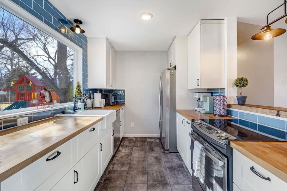 Find balance in every corner of this kitchen, where functionality meets style with cabinetry, sink, and microwave on one side, and fridge, coffee maker, K-cups, and stove on the other.
