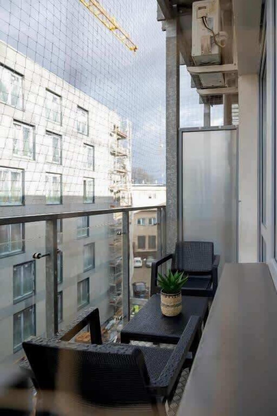 A small yet inviting balcony with a glass railing, offering a relaxing spot to enjoy the city view.

