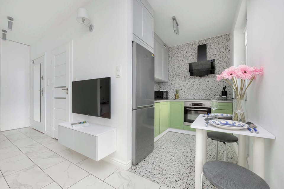 A sleek entertainment area with a mounted TV, white cabinetry, and modern lighting.
