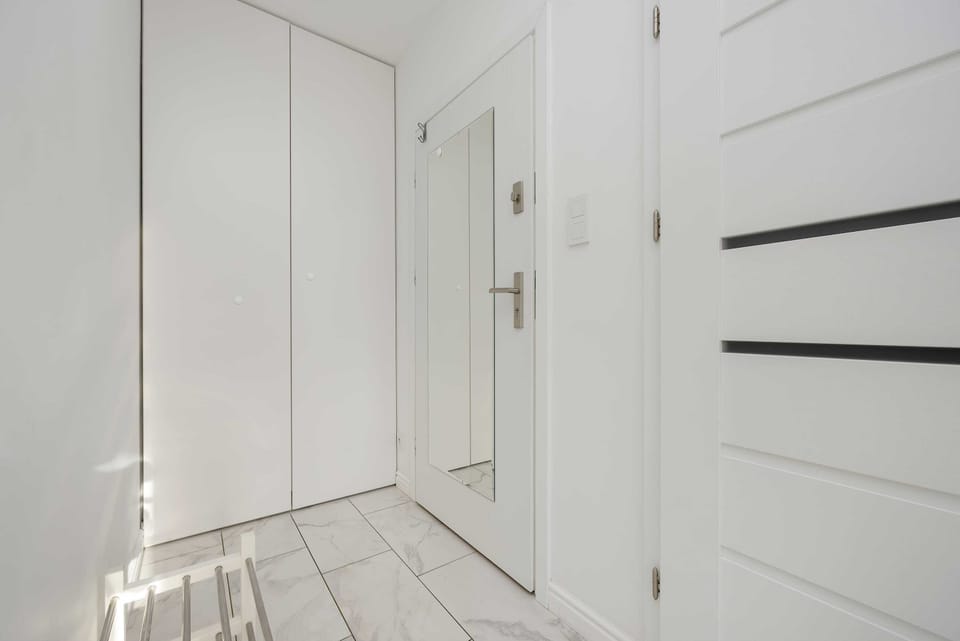 A spacious and bright open-plan living area with white floors, walls, and elegant furnishings.

