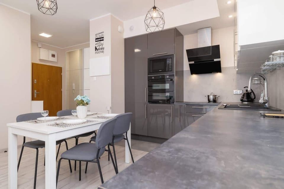 A wider view of the kitchen and dining area, featuring a dark accent wall and a combination of modern and industrial design elements.

