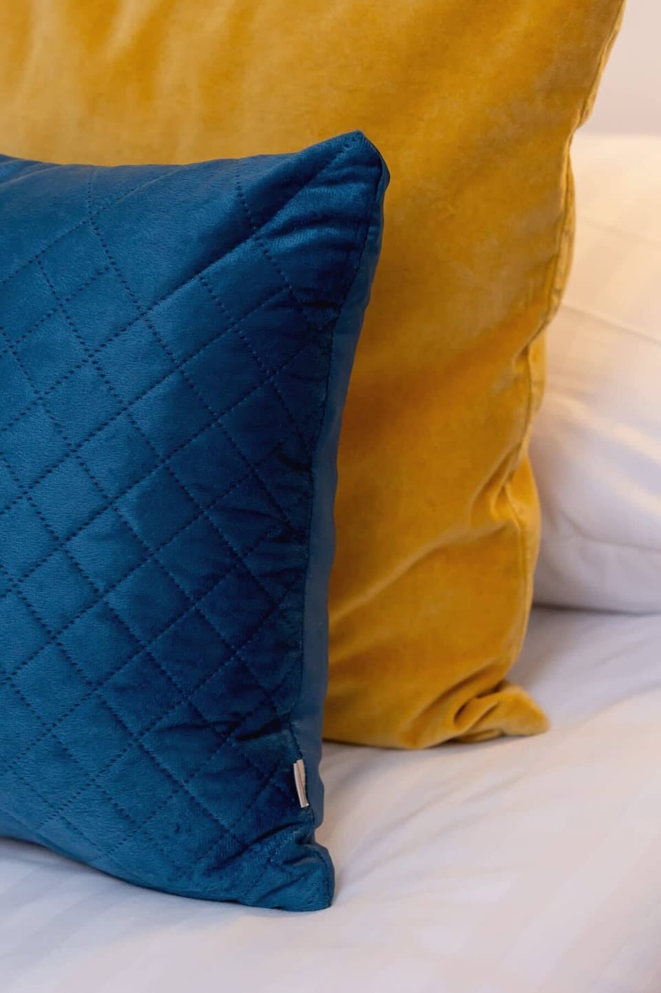 A close-up of the bedroom decor, emphasizing the contrast between the deep blue cushions and warm yellow accents, adding a stylish and inviting touch.

