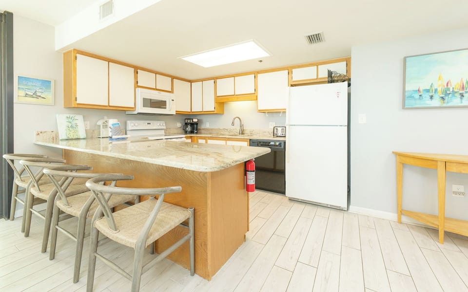 Kitchen features a granite countertop, white cabinetry, and a breakfast bar with seating for four