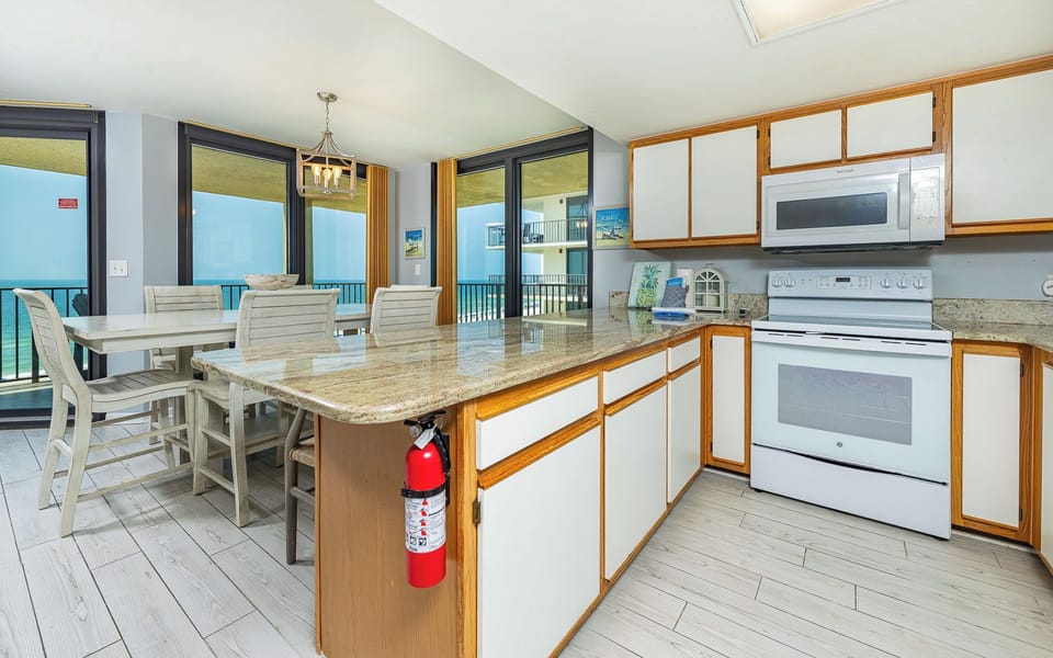Bright kitchen featuring granite countertops, white cabinetry, and a breakfast bar, perfect for meals or enjoying coffee