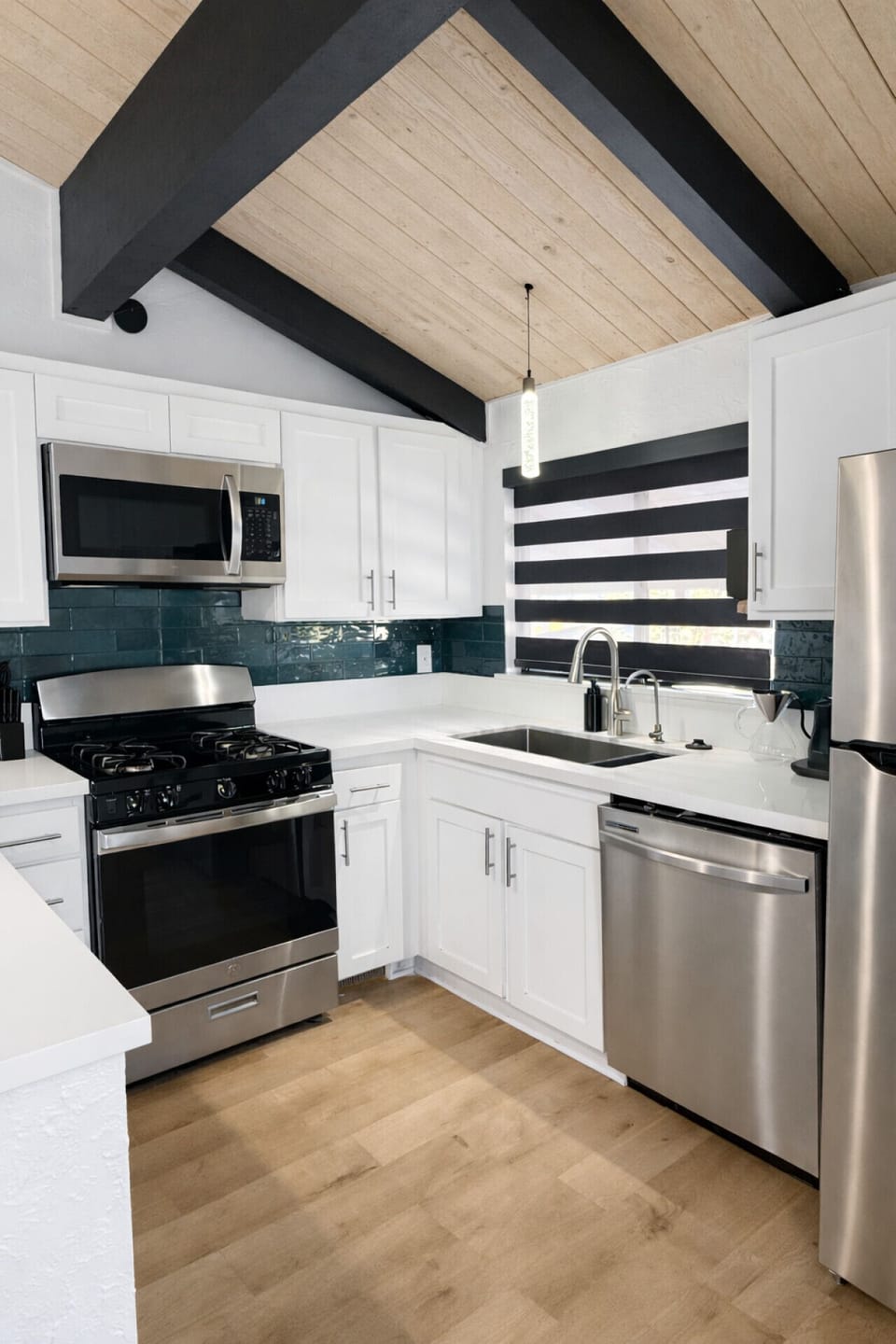 Fully equipped kitchen with stainless steel appliances, including microwave, oven, dishwasher, and refrigerator — stocked with everything you need to cook at home.