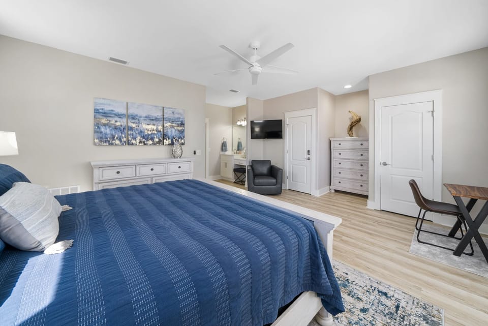 Unwind in your spacious master suite featuring a plush king bed, private seating area, and coastal artwork that sets a serene mood.