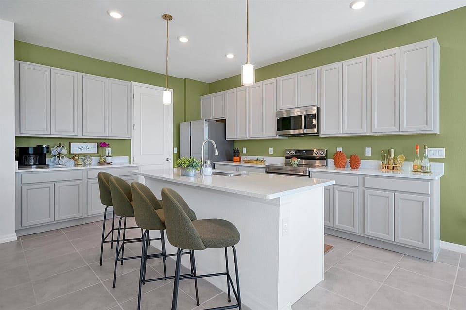Sleek kitchen w/ white cabinetry, island seating & stainless steel appliances.
