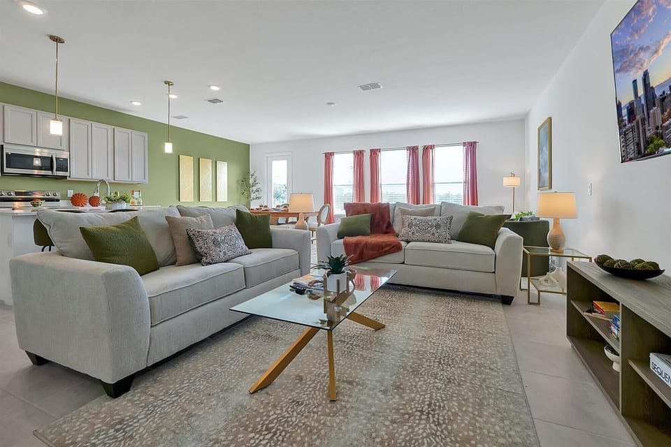 Bright living room w/ comfy neutral sofas & natural light pouring in.
