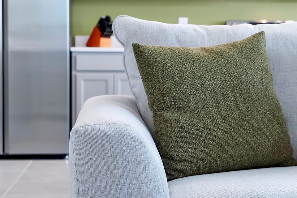 Plush sofa detail w/ a sage green throw pillow — sink in & unwind.
