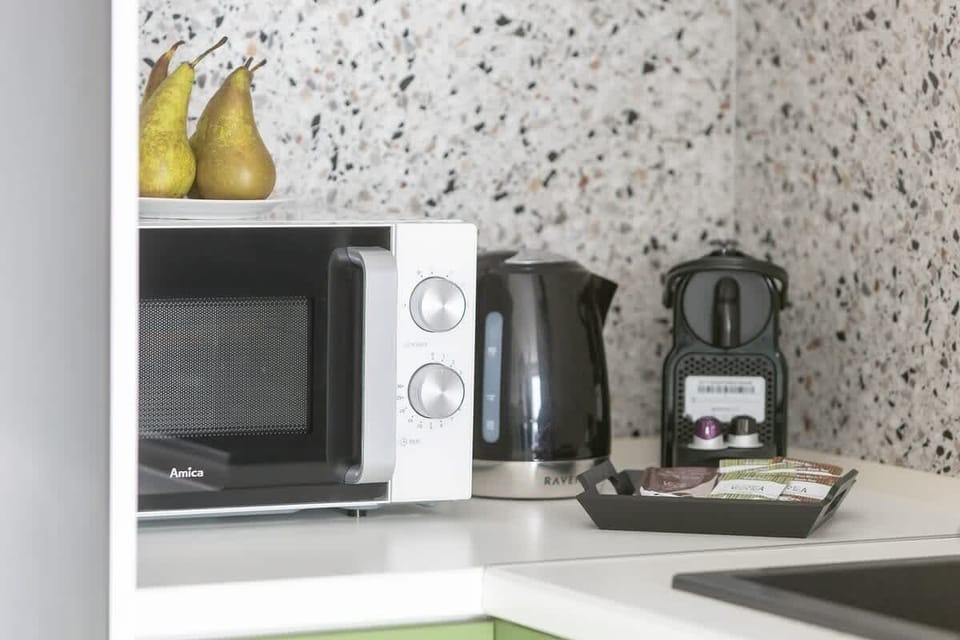 A close-up of the kitchenette countertop with a microwave, coffee maker, and stylish terrazzo backsplash.
