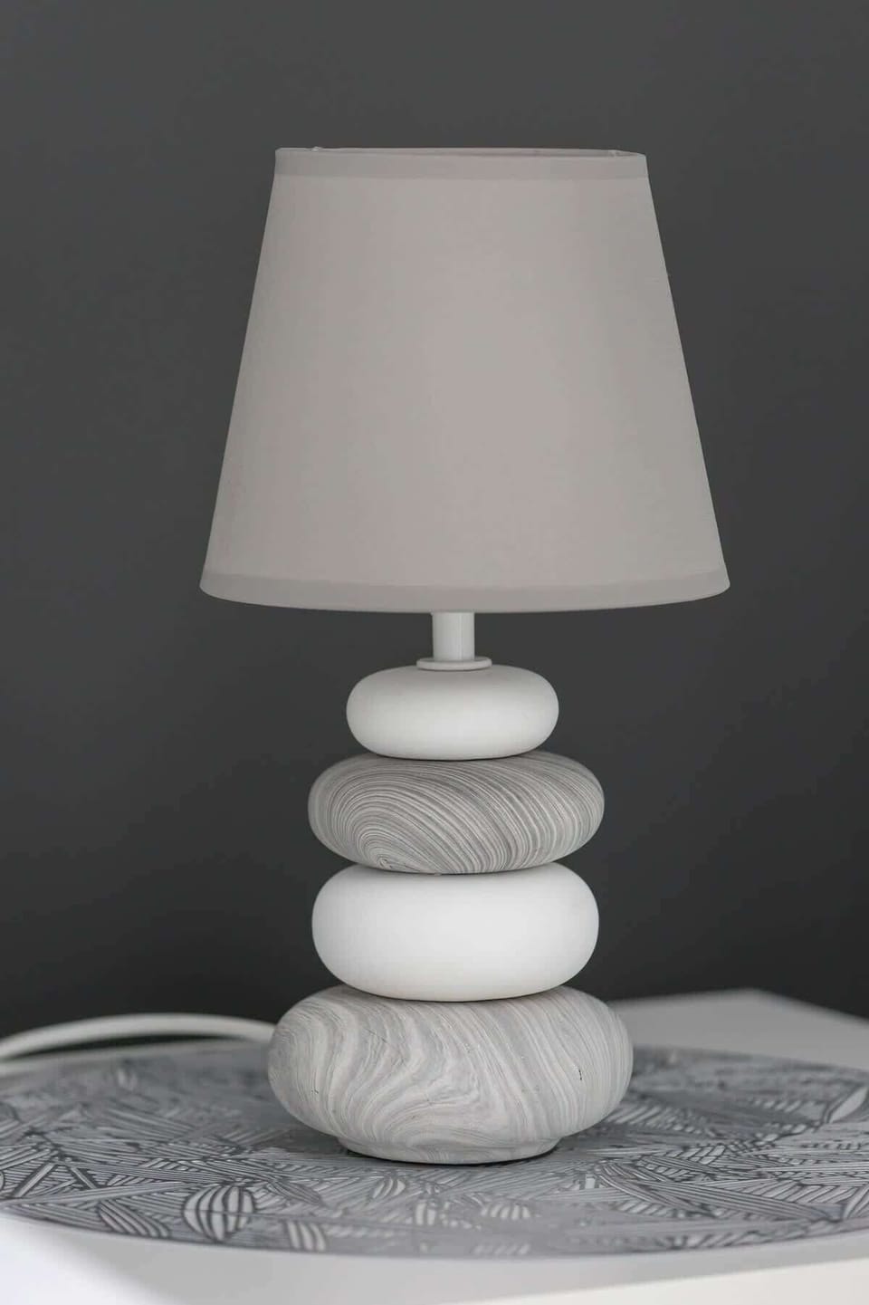 A close-up of a modern white table lamp with a sculptural base.
