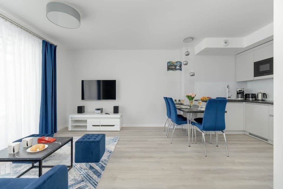 A bright and elegant kitchen and dining area with blue chairs and a minimalist aesthetic.
