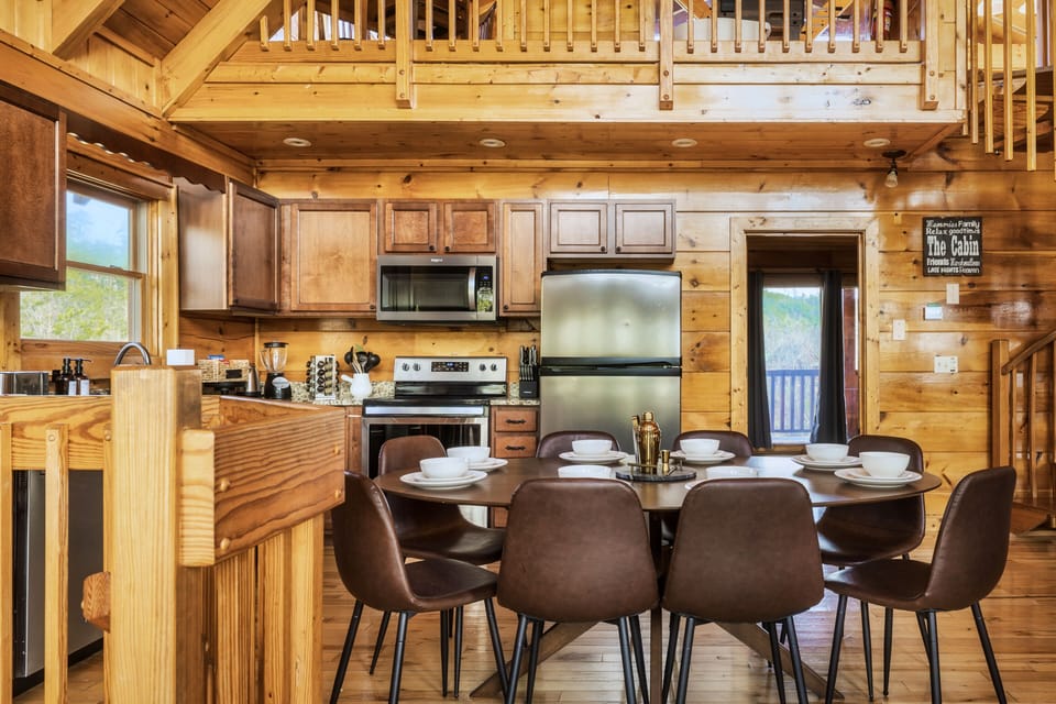 Open space kitchen and dining area with Cathedral ceiling and wooden views.