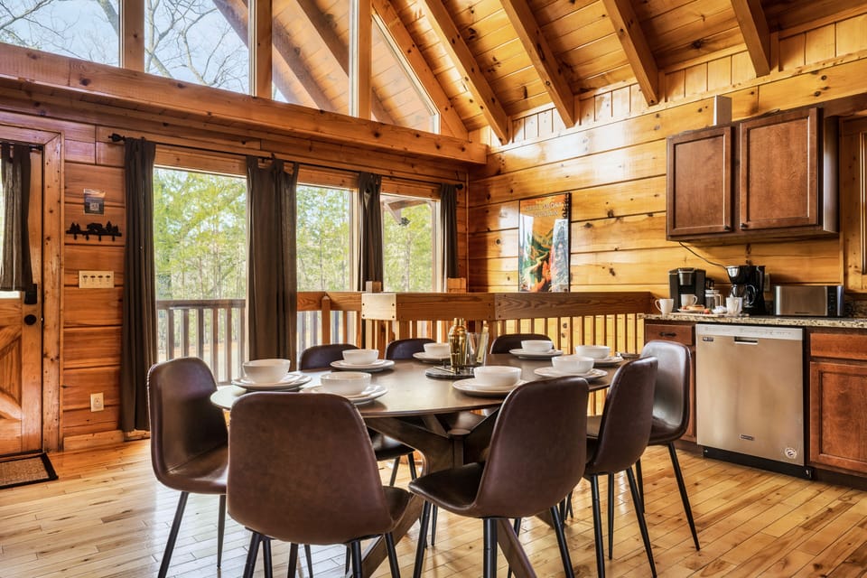 Open space kitchen and dining area with Cathedral ceiling and wooden views.