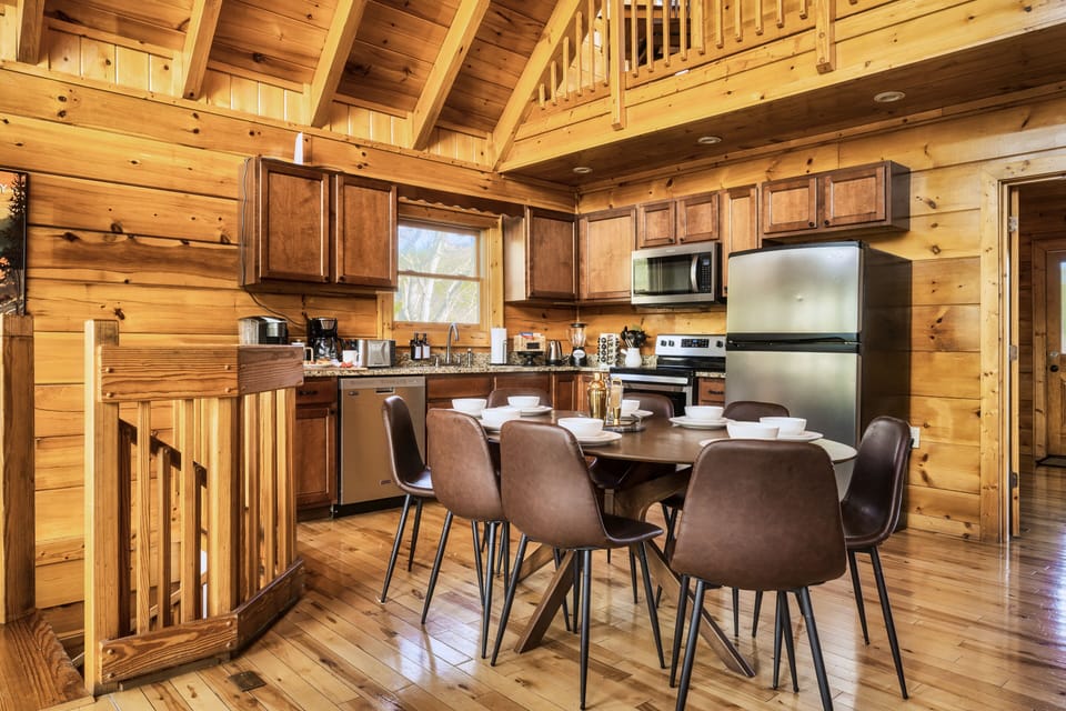 Open space kitchen and dining area with Cathedral ceiling and wooden views.