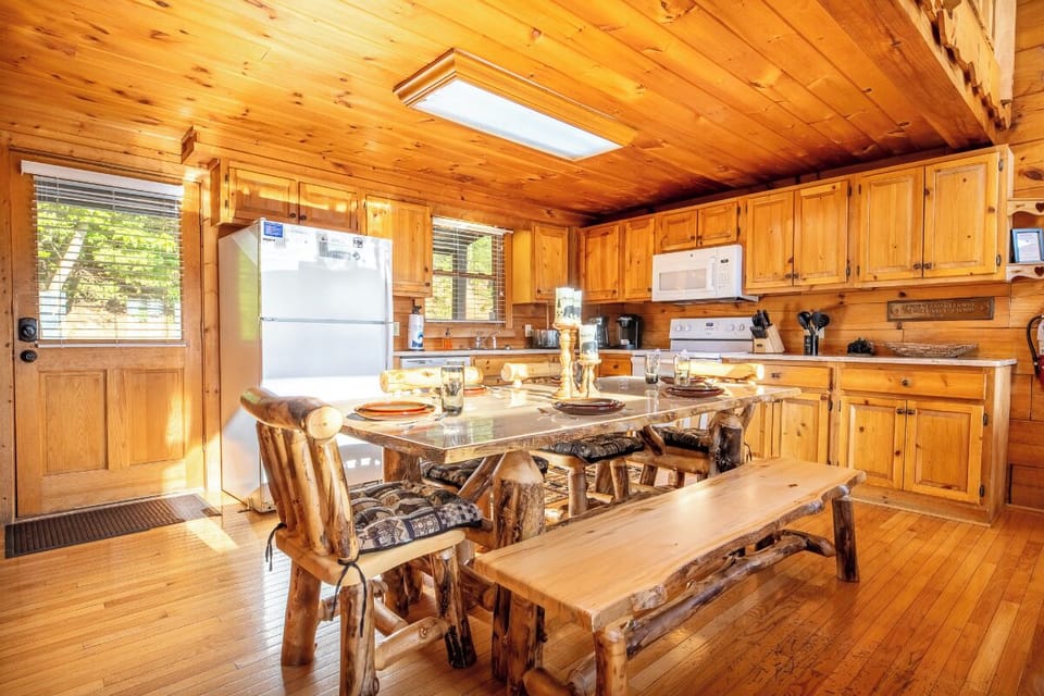Gather around this handcrafted log dining table in your fully equipped cabin kitchen, where rustic charm meets modern convenience for memorable meals together.