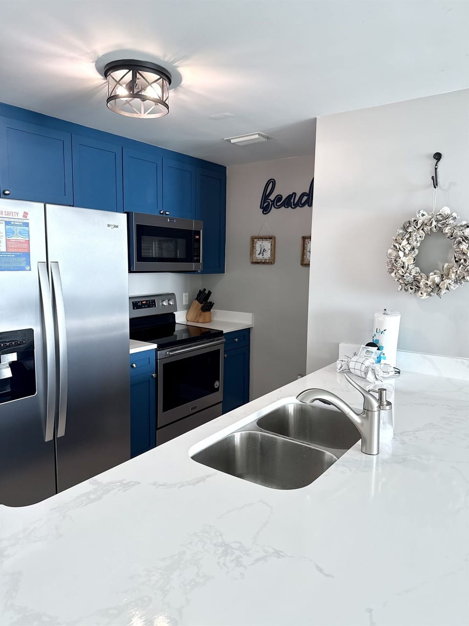 Your fully equipped kitchen features stunning blue cabinets, stainless steel appliances, and pristine marble countertops perfect for preparing meals during your beach getaway.