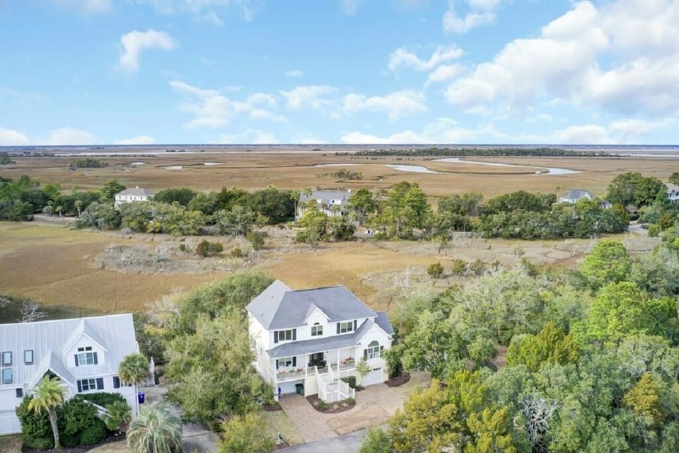 Elegant multi-story home nestled in beautiful greenery with sweeping marshland views stretching out to the horizon.
