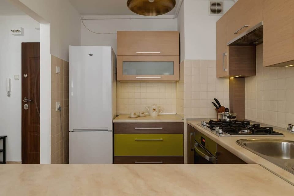 A functional kitchen area with a mix of green and wooden cabinetry, a gas stove, and practical storage solutions, ensuring efficiency in meal preparation.

