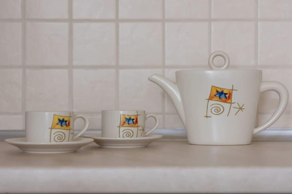 A close-up of a tea set on a tiled kitchen counter, featuring charming decorative elements for a cozy and homey feel.

