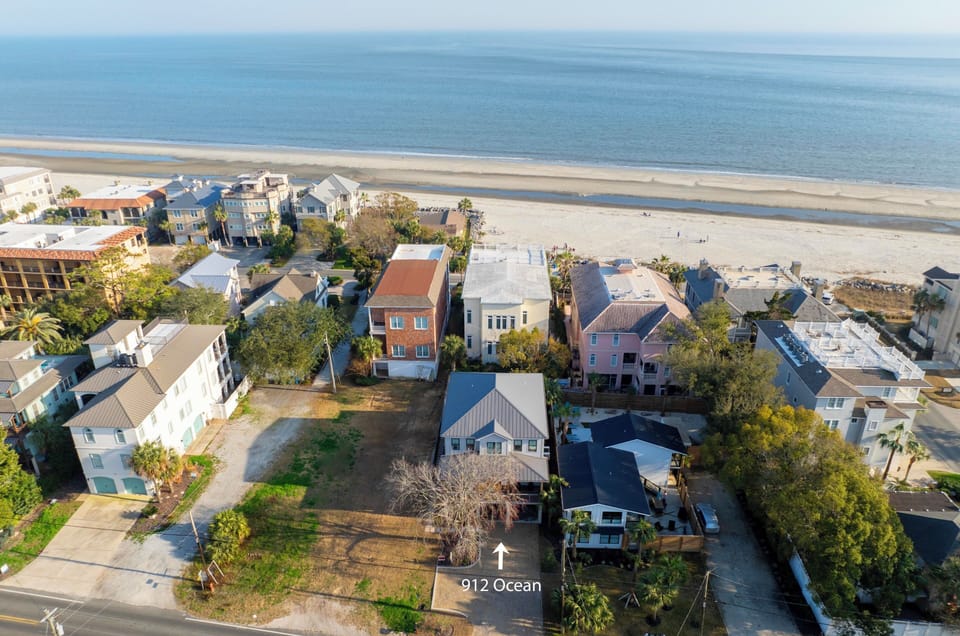 Aerial view of beachfront properties showcasing the coastal neighborhood and expansive sandy beach stretching along the ocean.
