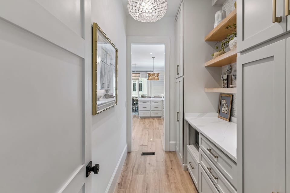 Step into this bright hallway with built-in storage and beautiful floating shelves, creating your perfect entry into the elegant kitchen beyond.