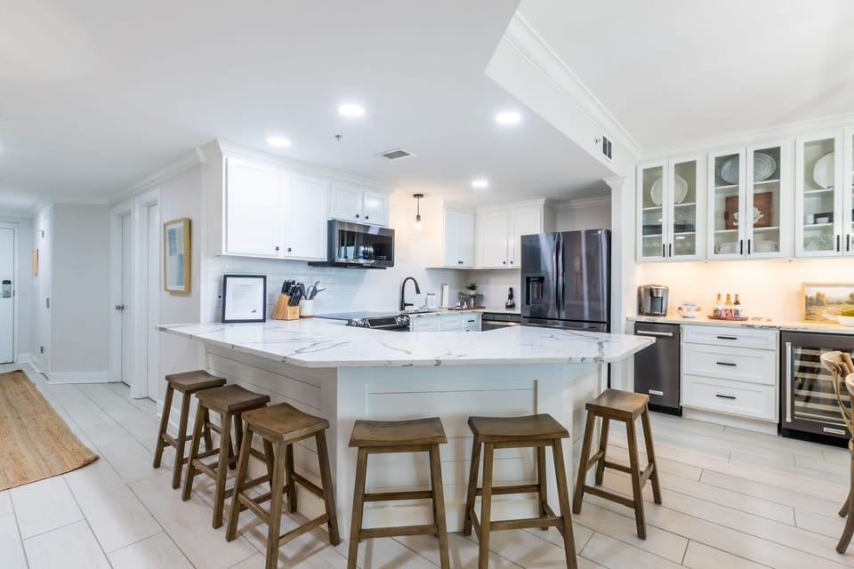 Prepare meals and enjoy casual dining in this stunning kitchen design, featuring modern appliances and a wet bar area