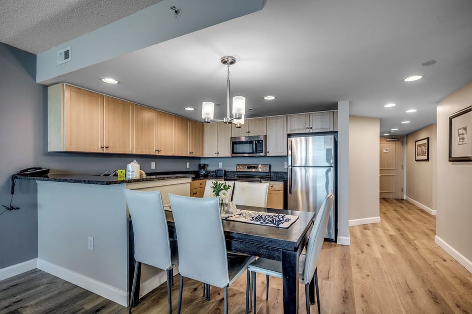Sleek kitchen and dining with wood cabinets, granite counters, and lighting