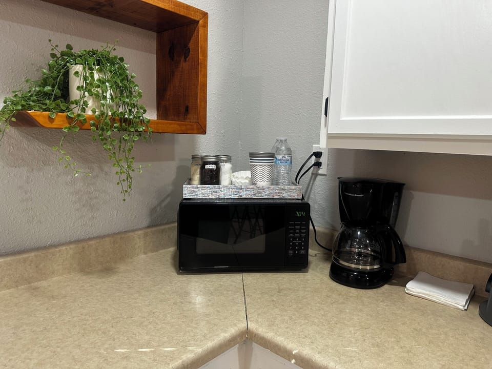 Microwave, coffee maker, coffee, sugar, creamer, coffee filters and waters.