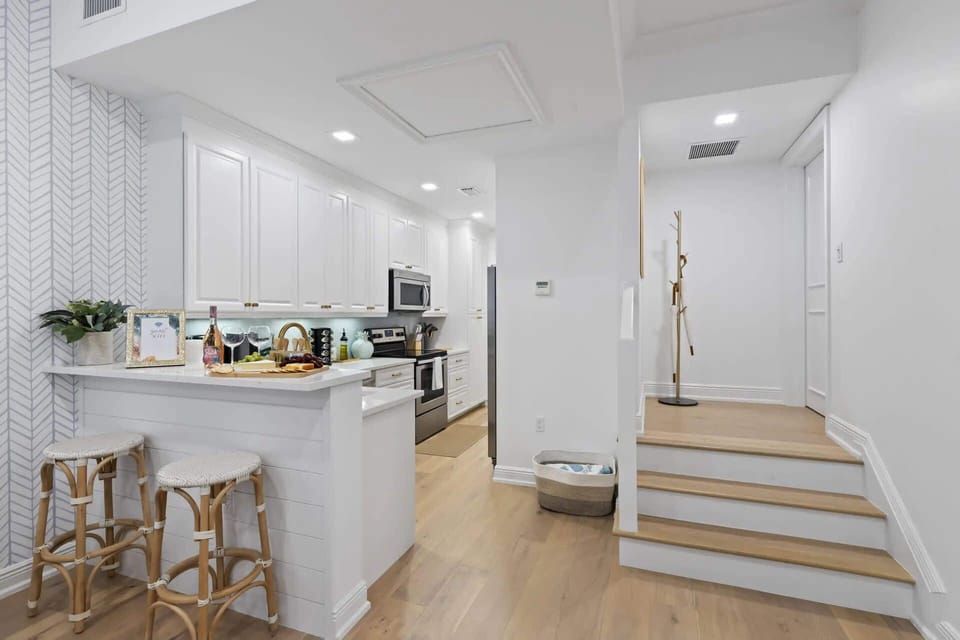 Modern kitchen with white cabinetry and a breakfast bar with stools.